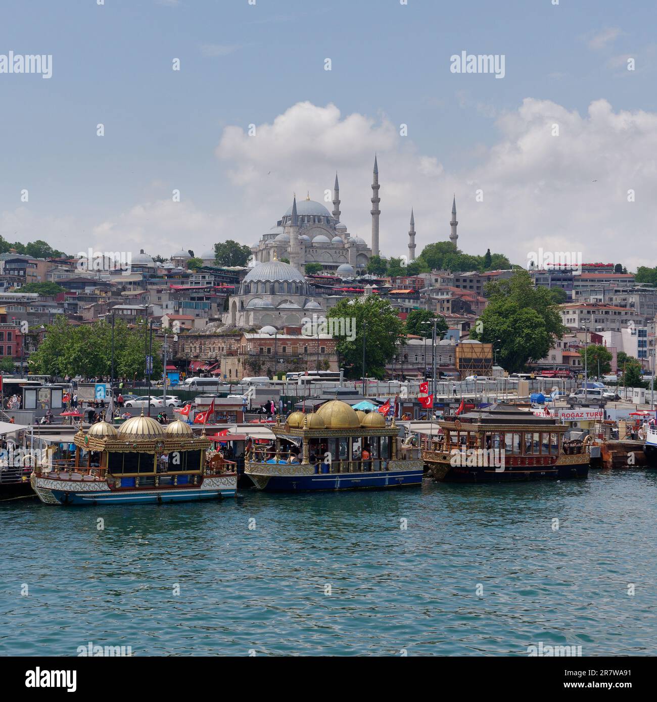 Goldene Kuppelboote, die Fischsandwichen am Goldenen Horn mit der Suleymaniye-Moschee auf dem Hügel in Istanbul, Türkei verkaufen Stockfoto