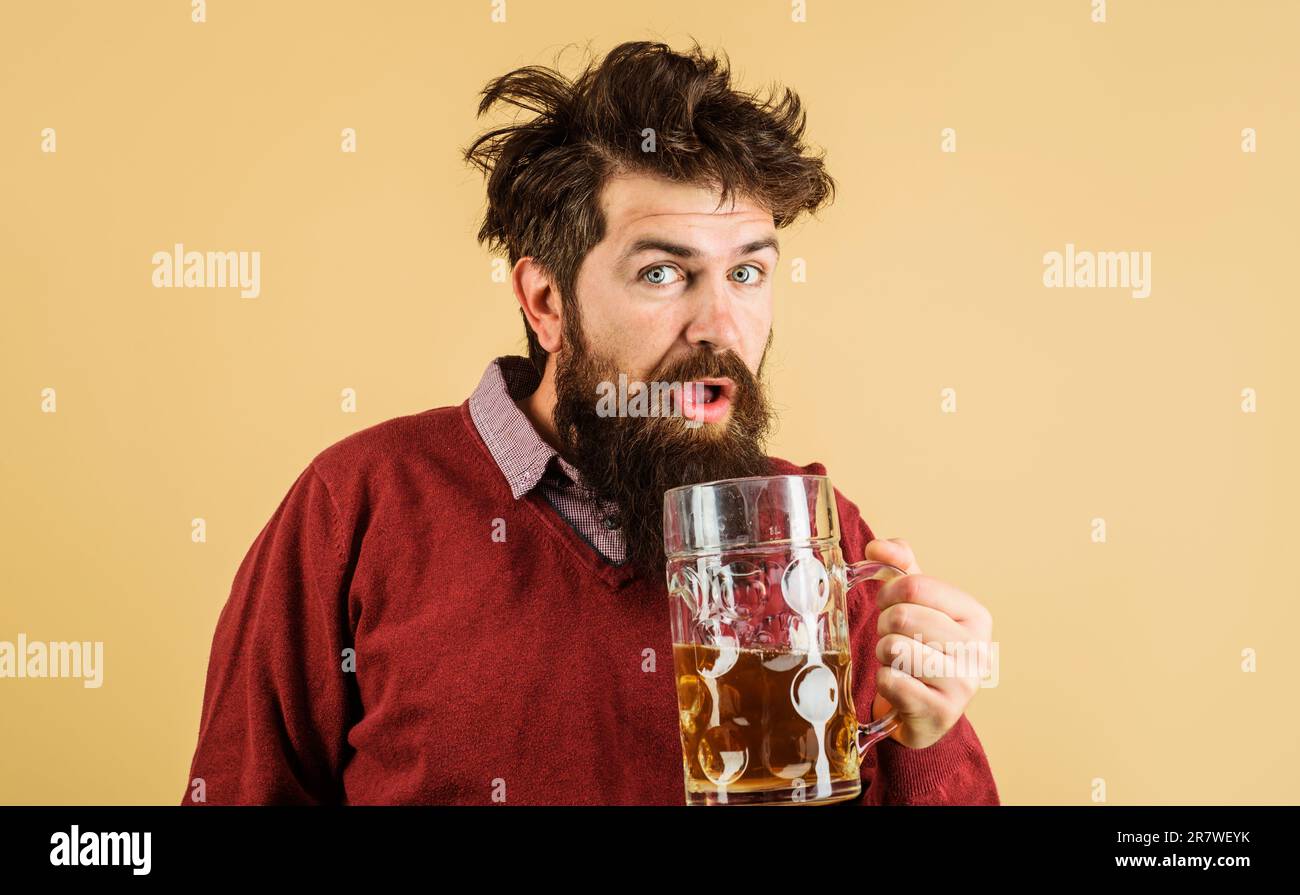 Ein bärtiger Mann beim oktoberfest trinkt Bier. Überraschter bärtiger Mann mit Craft-Bier. Ein gutaussehender Mann, der frisch gezapftes Bier trinkt. Trunkenheitsverkostung Stockfoto