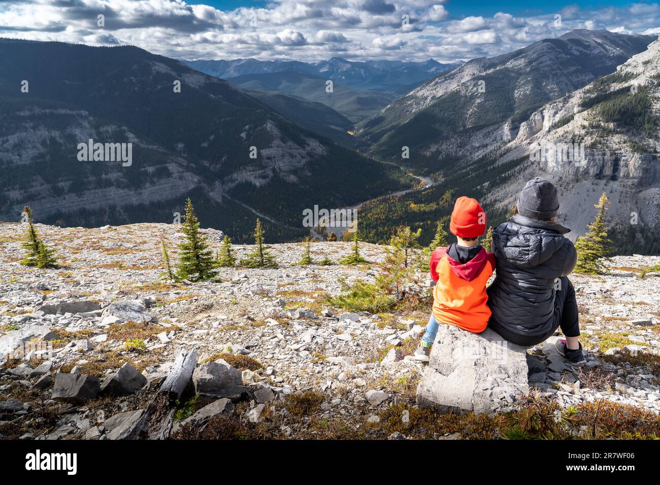 Bruder und Schwester sitzen auf einem Felsen mit Blick auf die kanadischen Rocky Mountains und Tälern in Herbstfarben auf der schönen Bragg Creek Alb am Moose Mountain Stockfoto