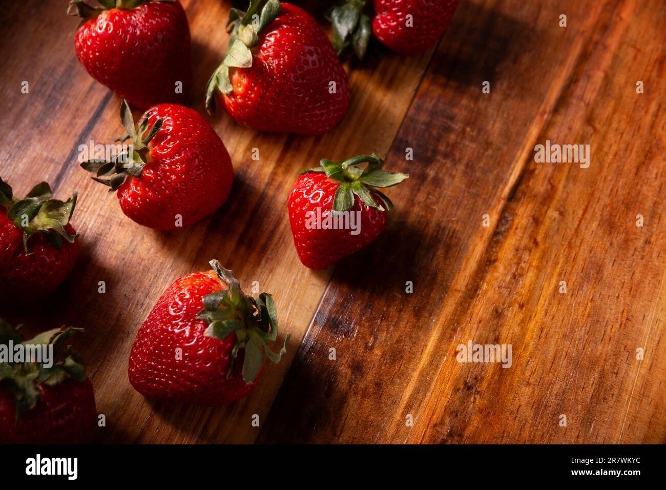 Frische Bio-Erdbeeren (fragaria) auf Holztisch. In einigen spanischsprachigen Ländern auch als Frutilla bekannt, ist es eine Waldfrucht, die gegessen wird A Stockfoto