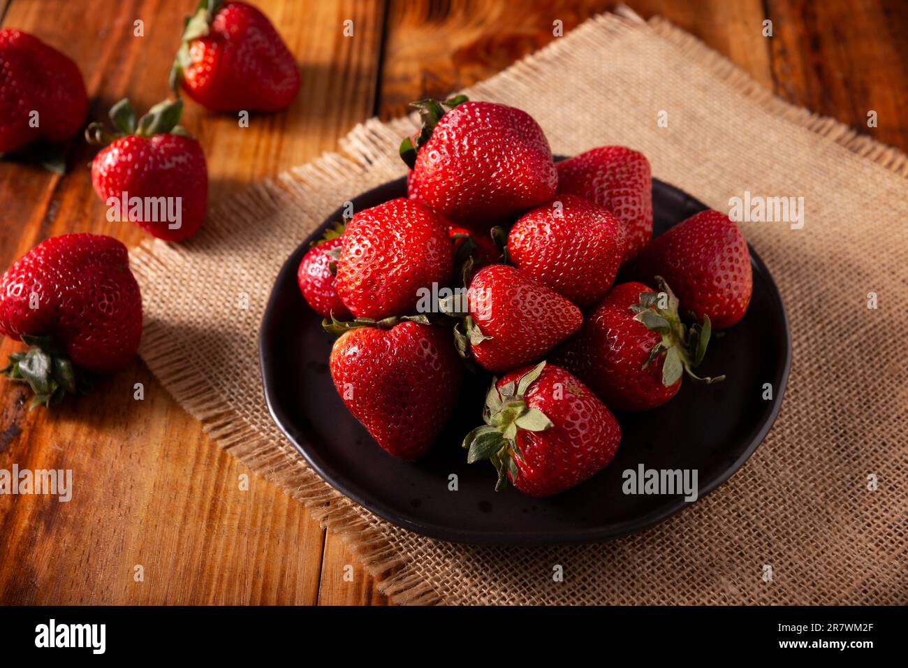 Frische Bio-Erdbeeren (fragaria) auf Holztisch. In einigen spanischsprachigen Ländern auch als Frutilla bekannt, ist es eine Waldfrucht, die gegessen wird A Stockfoto