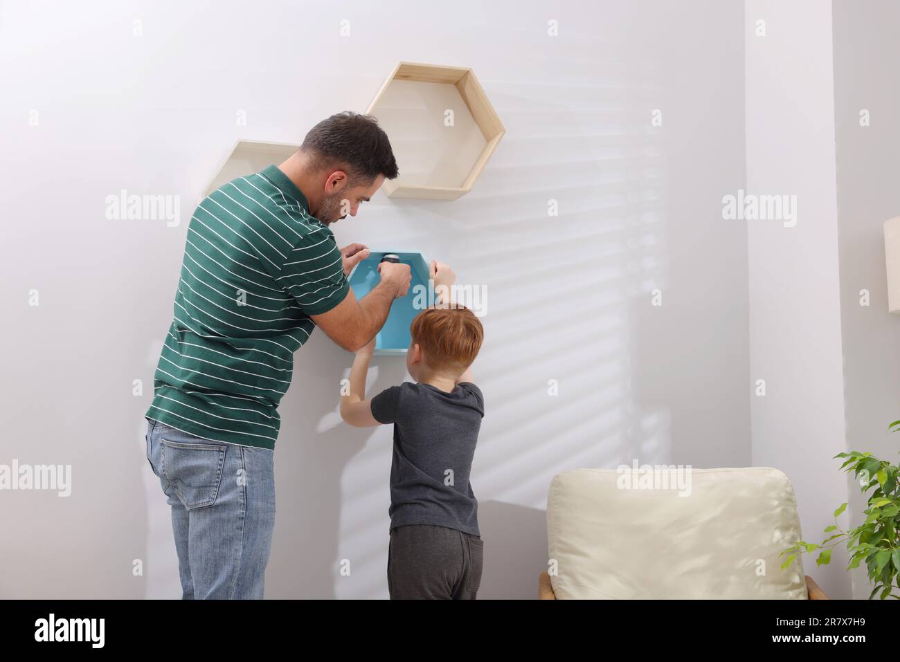 Vater und Sohn installieren Regale an der Wand zu Hause. Reparaturarbeiten Stockfoto
