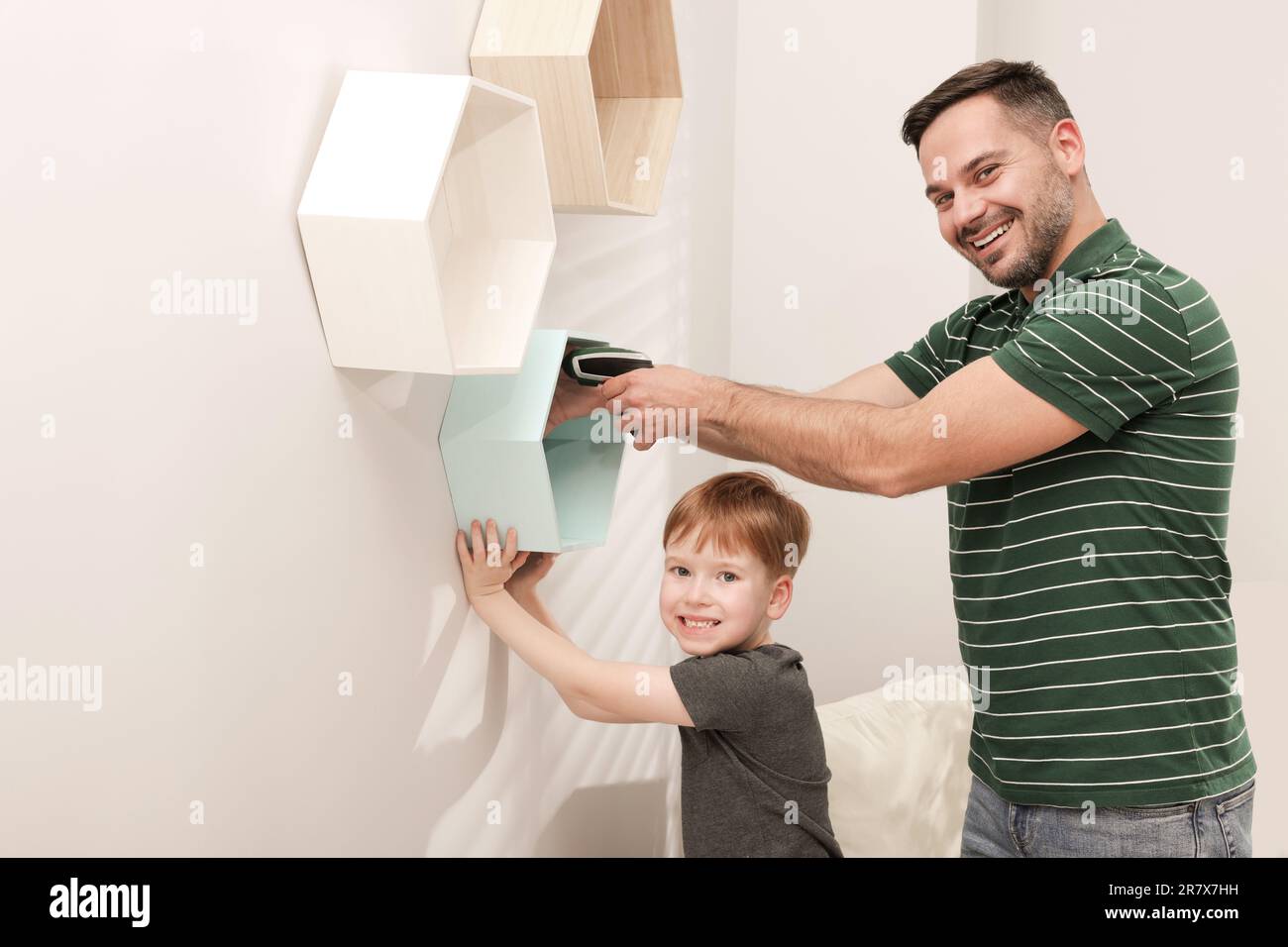 Vater und Sohn installieren Regale an der Wand im Haus. Reparaturarbeiten Stockfoto
