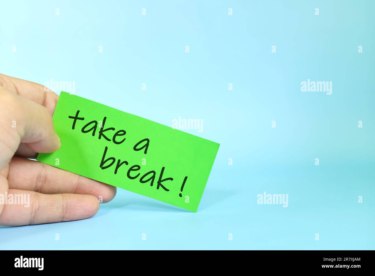 Erinnerungskonzept „Pause machen“. Eine Hand mit einem hellgrünen Mitteilungsbrief. Stockfoto