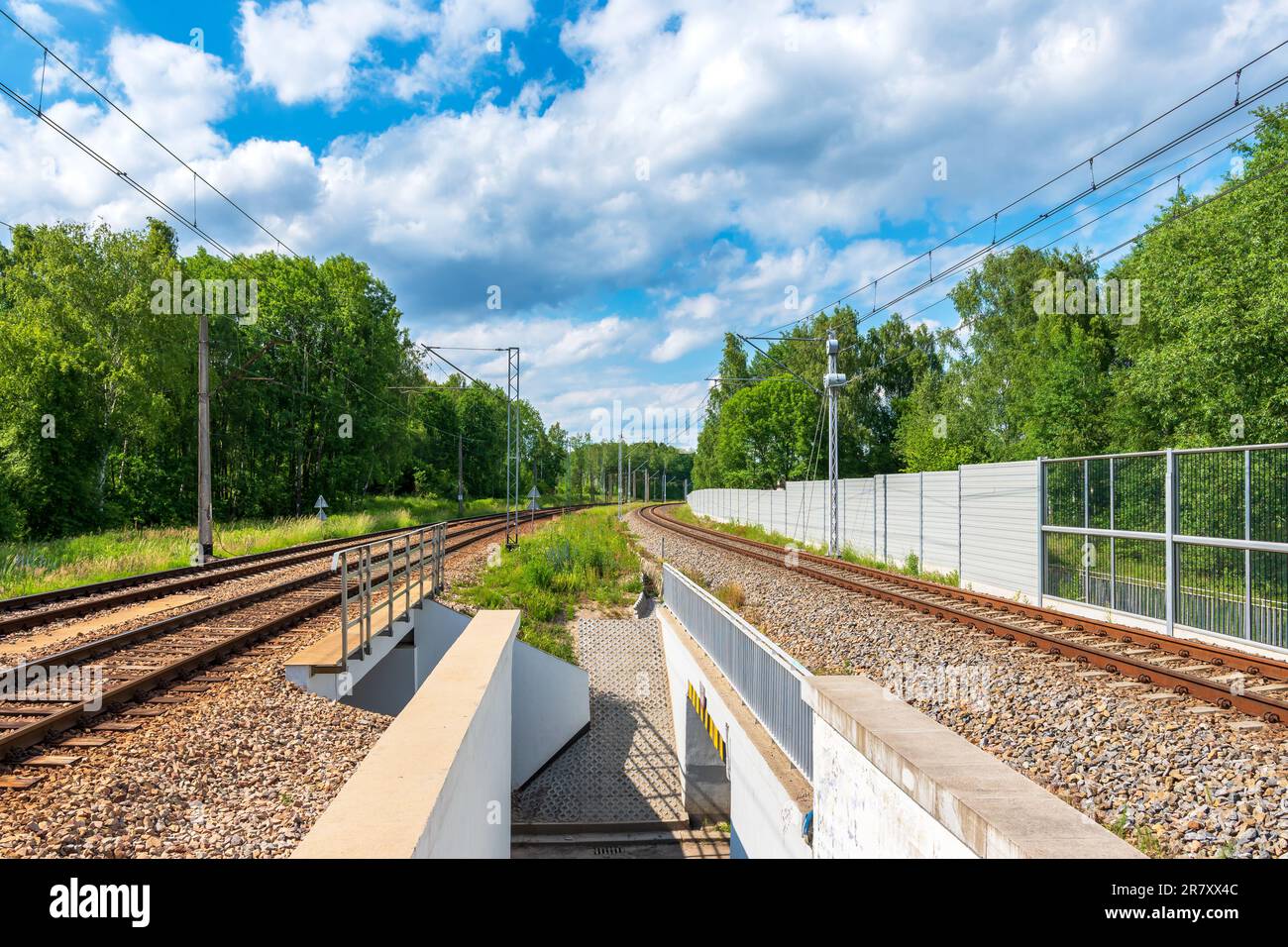 Eine kleine Eisenbahnbrücke. Tunnel unter der Eisenbahnlinie. Eisenbahnlinie durch den Wald an einem wunderschönen sonnigen Tag. Eisenbahntraktion Stockfoto