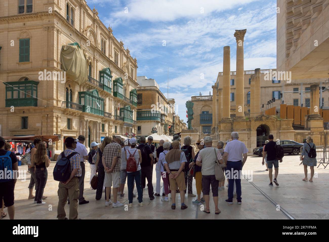 Gruppenreisen halten im Schatten, um den Erläuterungen des Reiseleiters in der Altstadt von Valletta, Malta, zu lauschen Stockfoto
