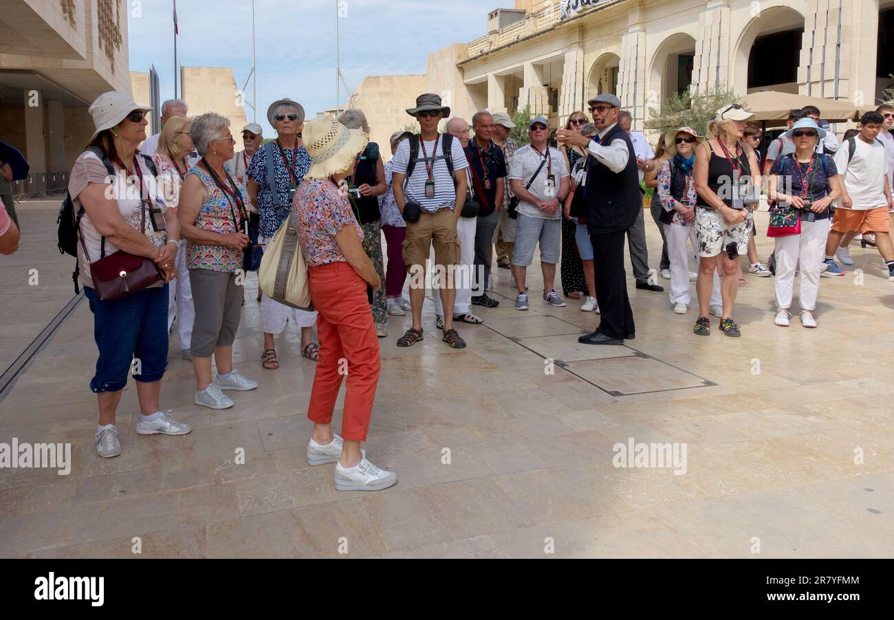 Der Reiseleiter hält die Gruppenreise im Schatten an, um ihm die rituellen Erklärungen über die Innenstadt von Valletta, Malta, zu geben Stockfoto