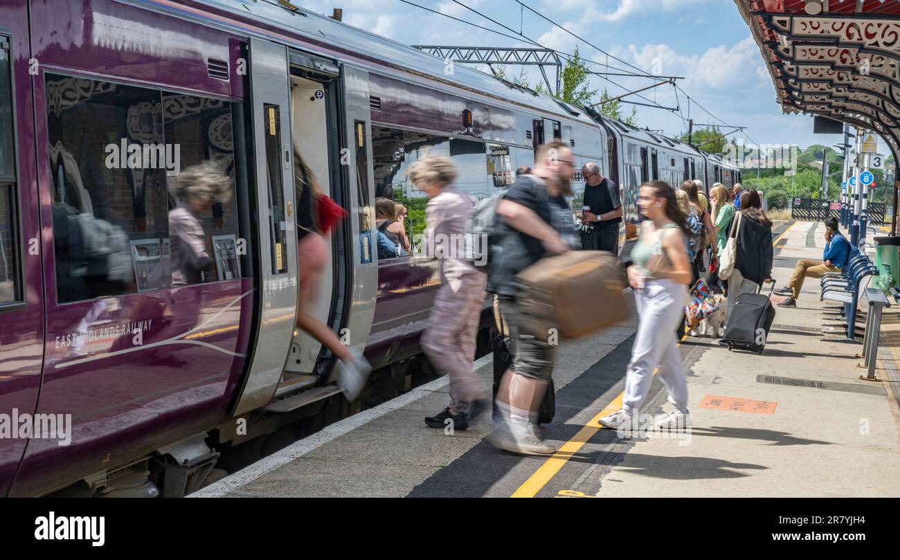 Bahnhof, Grantham, Lincolnshire, Großbritannien – Passagiere, die einen Zug der East Midlands Railway besteigen, der gerade auf einem Bahnsteig angekommen ist Stockfoto