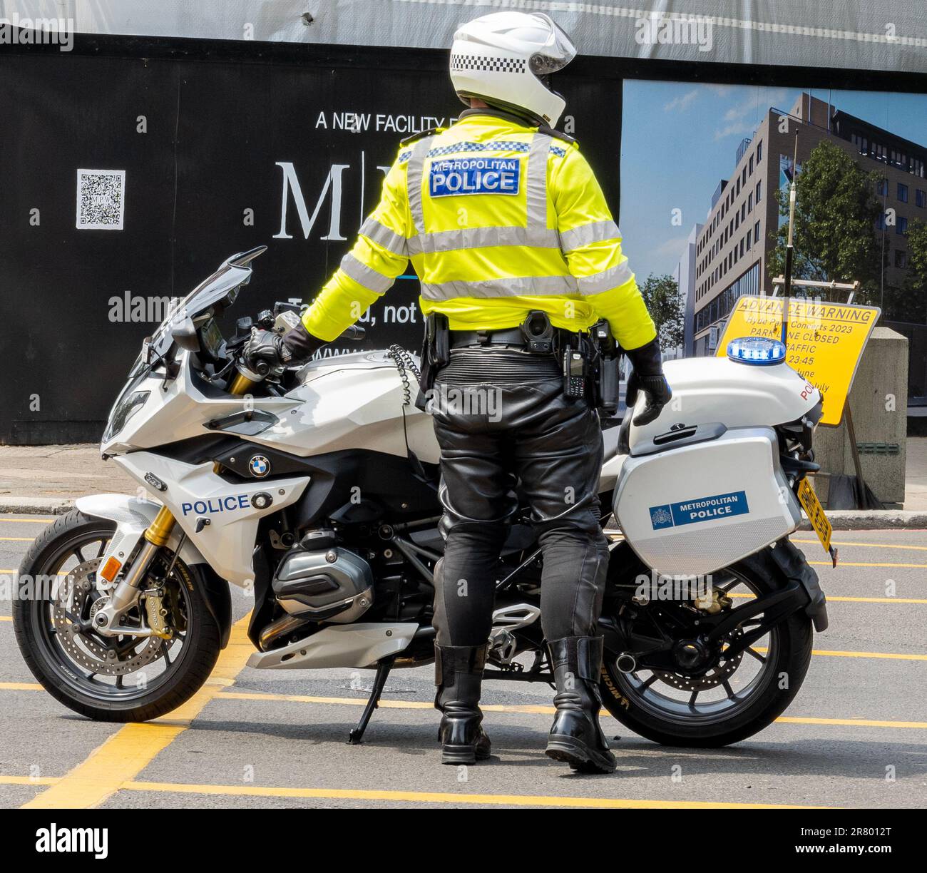 Polizeimotorrad mit Fahrer neben dem Motorrad in gelber Warnjacke Stockfoto