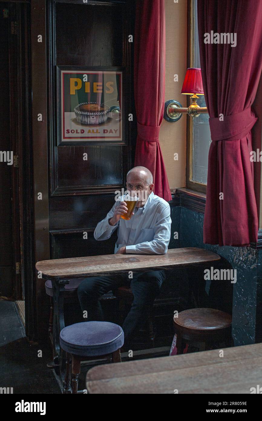 Männlicher, der ein Pint Bier im traditionellen Pub Guinea Grill in Mayfair, London, Großbritannien trinkt Stockfoto