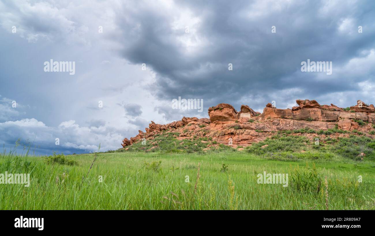 Stürmische Wolken über Sandsteinklippen und grüne Prärie in Colorado Foothills - Lory State Park im Spätfrühling Stockfoto