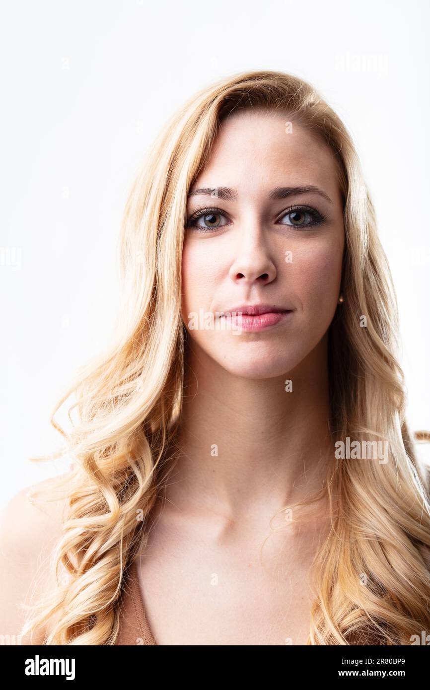 Das frontseitige Porträt einer selbstbewussten blonden Frau. Ihr stummes Lächeln scheint durch ihre Augen. Weißer Hintergrund verstärkt ihren Glanz Stockfoto