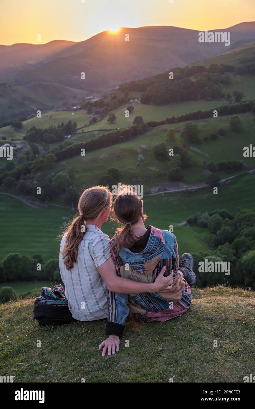 Ein junges Paar, das den Sonnenuntergang von Castell Dinas Brân, Llangollen, Wales aus beobachtet Stockfoto