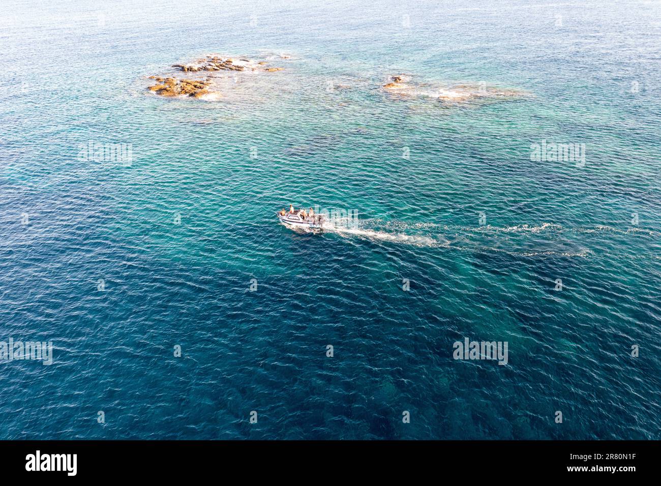 Das Schnellboot segelt im blau gewellten Hintergrund des Ägäischen Meeres neben Felsformationen. Tinos Island Kykladen, die Menschen genießen Sommerurlaub in Griechenland. Stockfoto