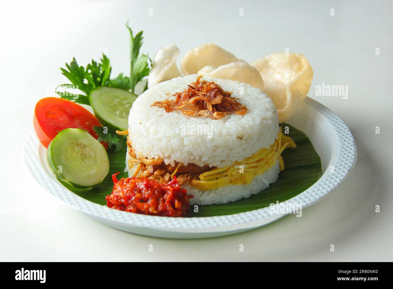 Indonesische Küche auf weißem Hintergrund. Reisburger mit scharfem Hühnchen, Eieromelette, Fisch, Sardelle, Rinderseide, Garnelen, Tomaten, Gurken, Sellerie Stockfoto