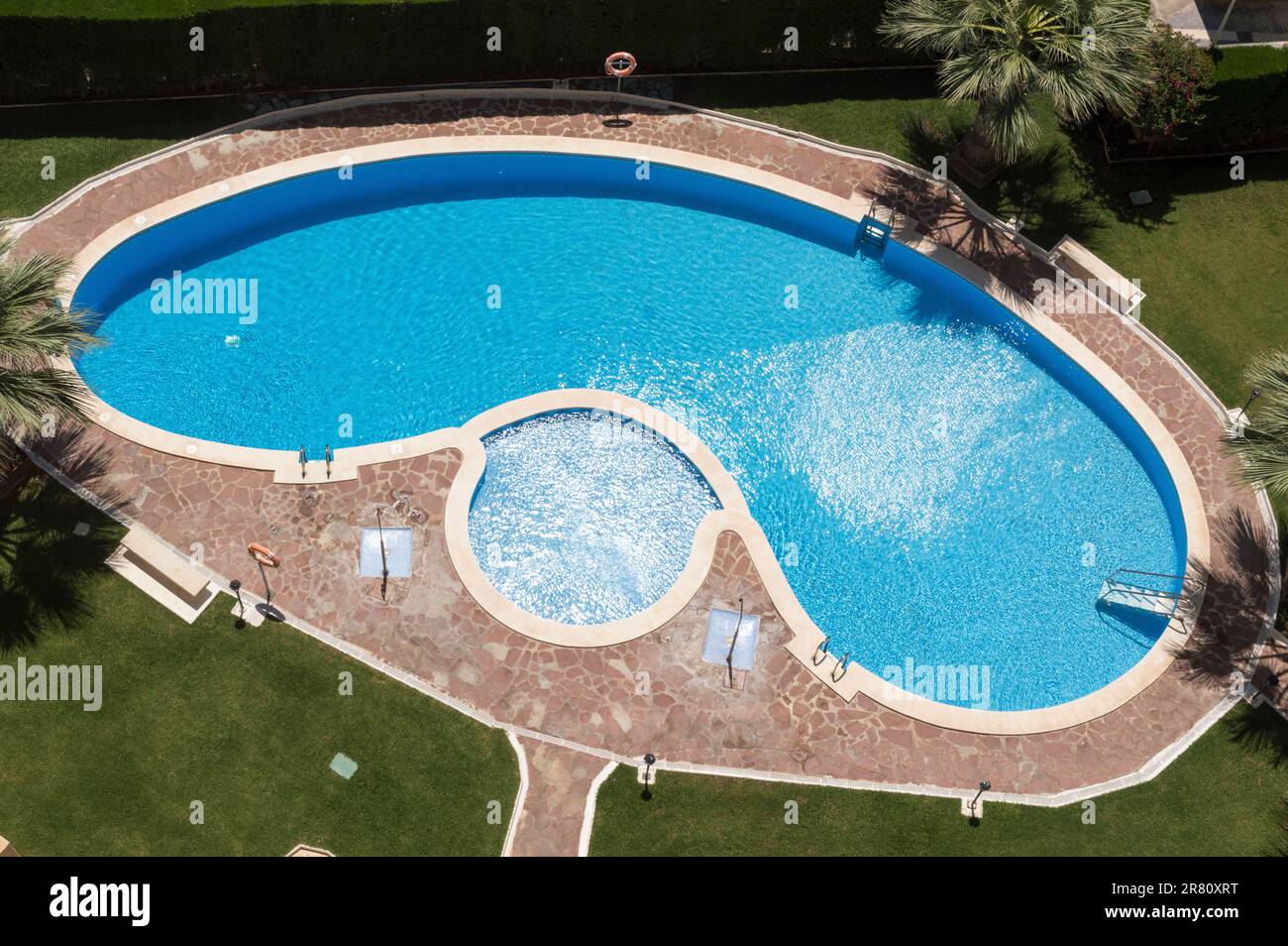 Luftbild eines nierenförmigen Pools mit klarem blauem Wasser. Stockfoto