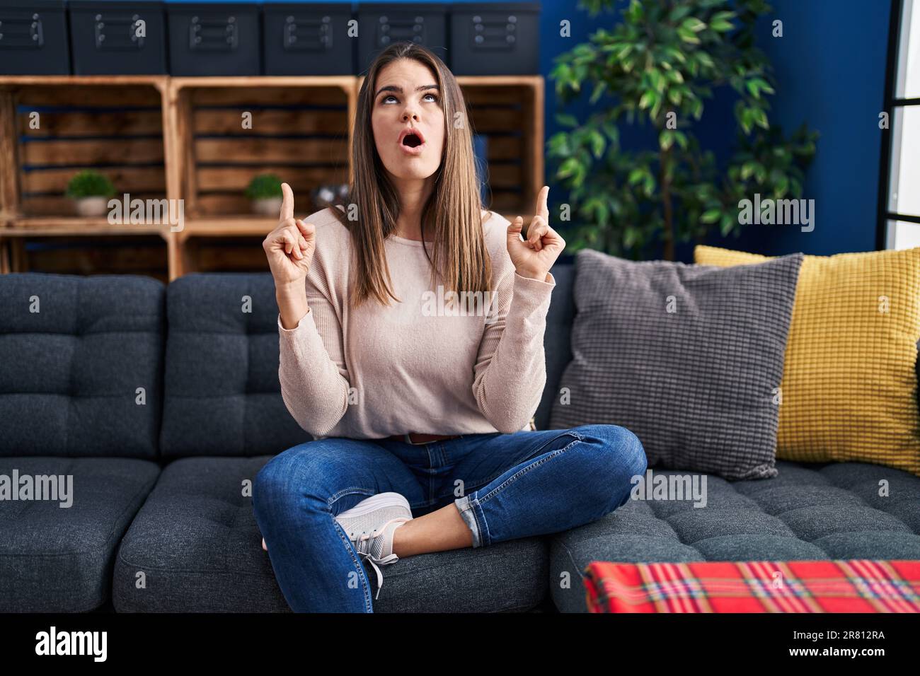 Eine wunderschöne Frau, die zu Hause auf dem Sofa saß, war erstaunt und überrascht, als sie