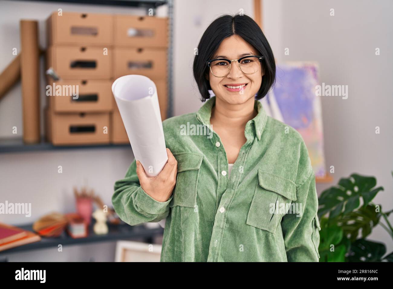 Eine junge asiatische Frau, die im Kunstatelier ein Papier in der Hand ...