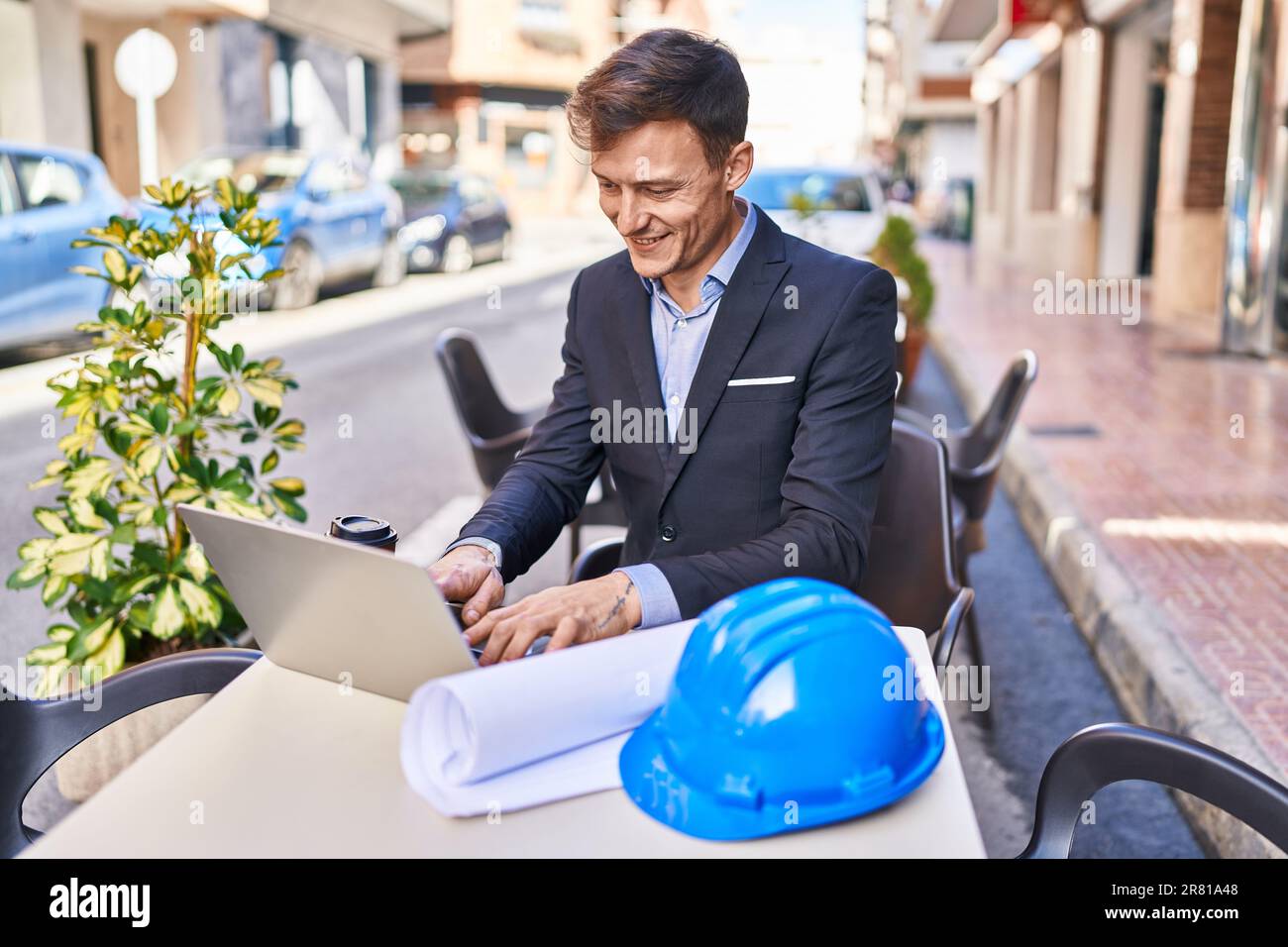 Junger Architekt mit Laptop, der auf dem Tisch auf der Terrasse des Cafés sitzt Stockfoto