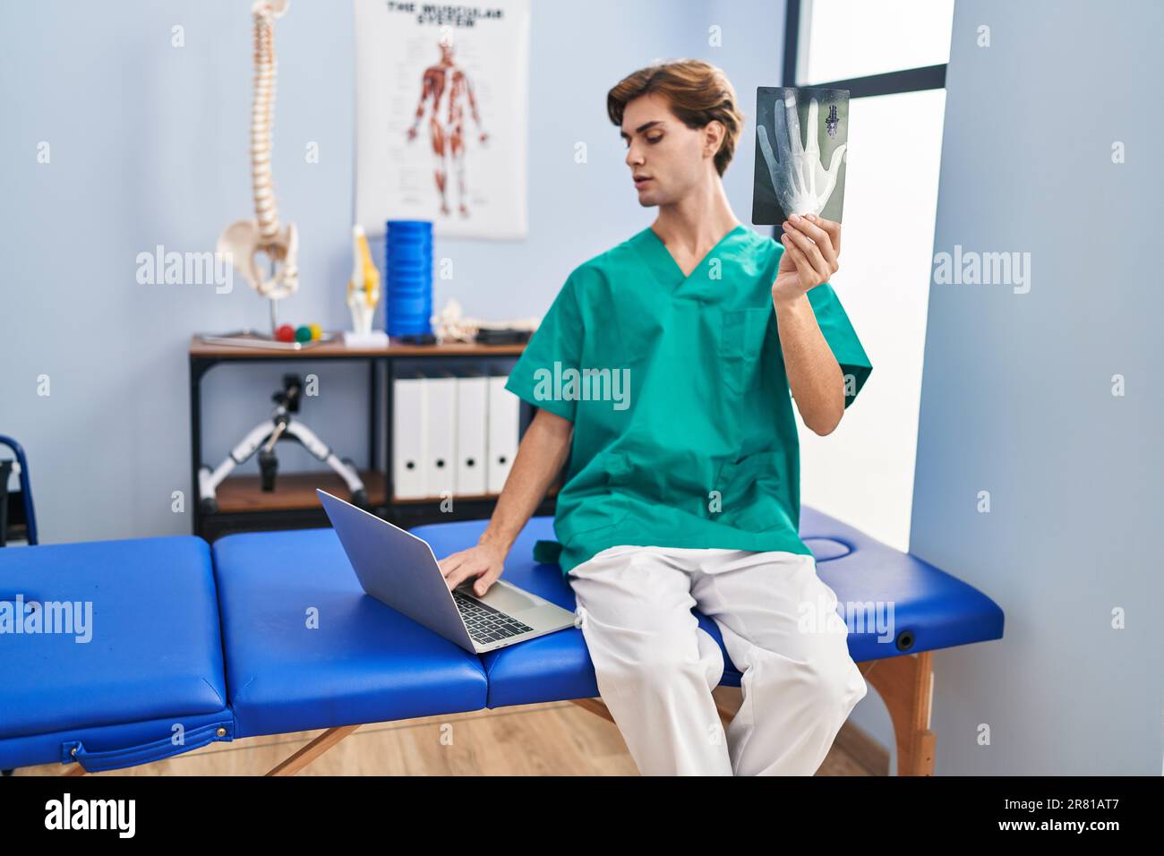 Junger weißer Physiotherapeut, der mit dem Laptop in der Reha-Klinik ...