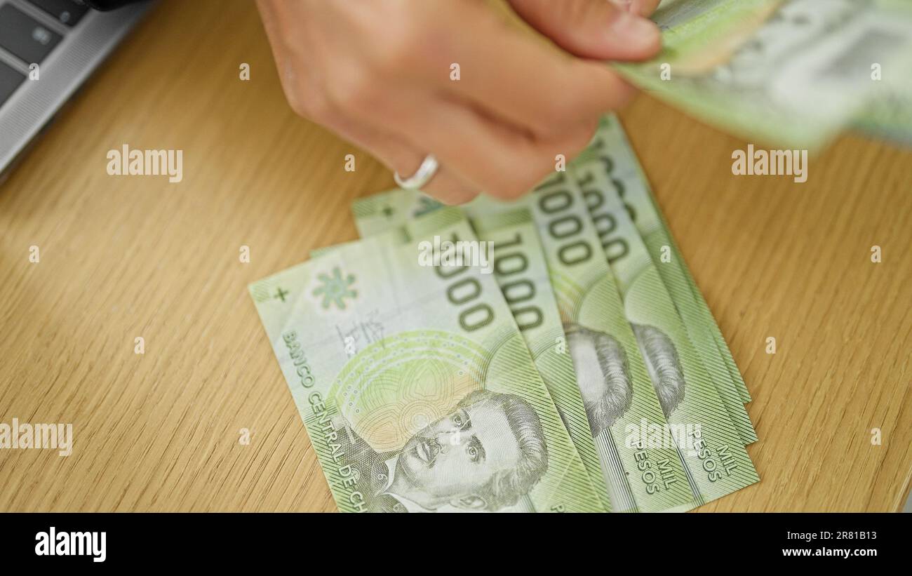 Junge, wunderschöne hispanische Frau, die im Büro chilenische Pesos-Banknoten zählt Stockfoto