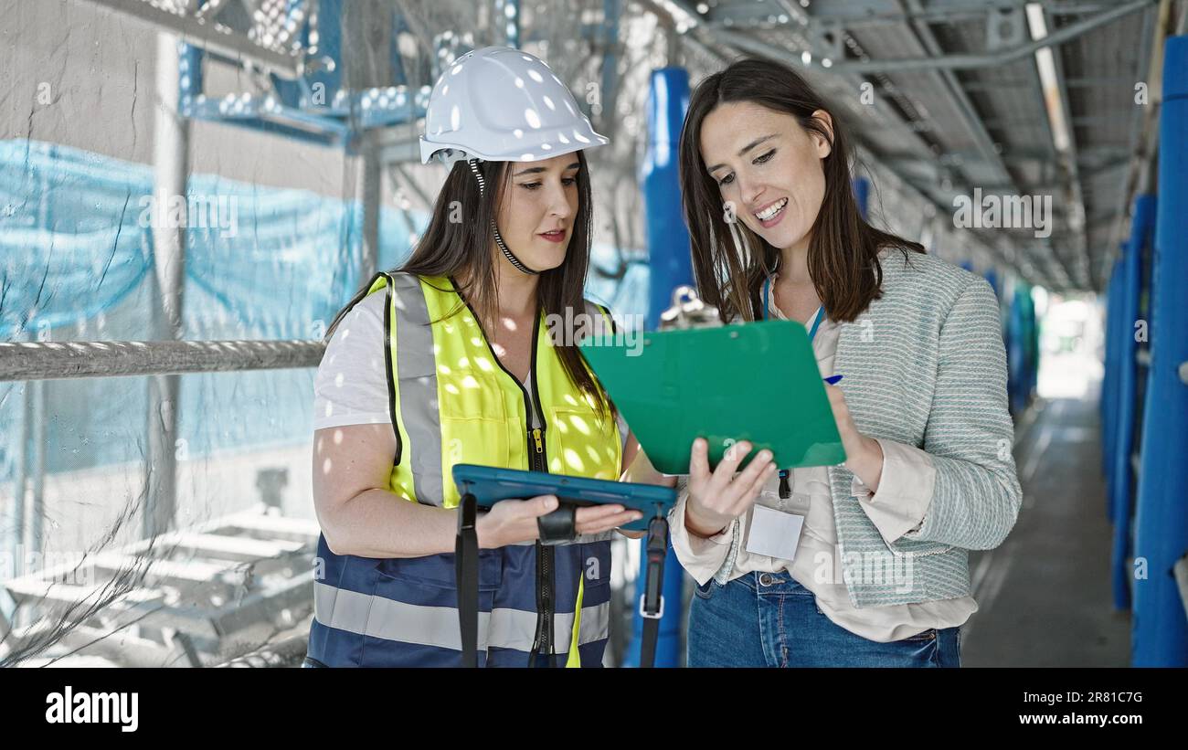 Zwei Architekten und Arbeiterinnen, die auf der Straße auf dem Touchpad schreiben Stockfoto