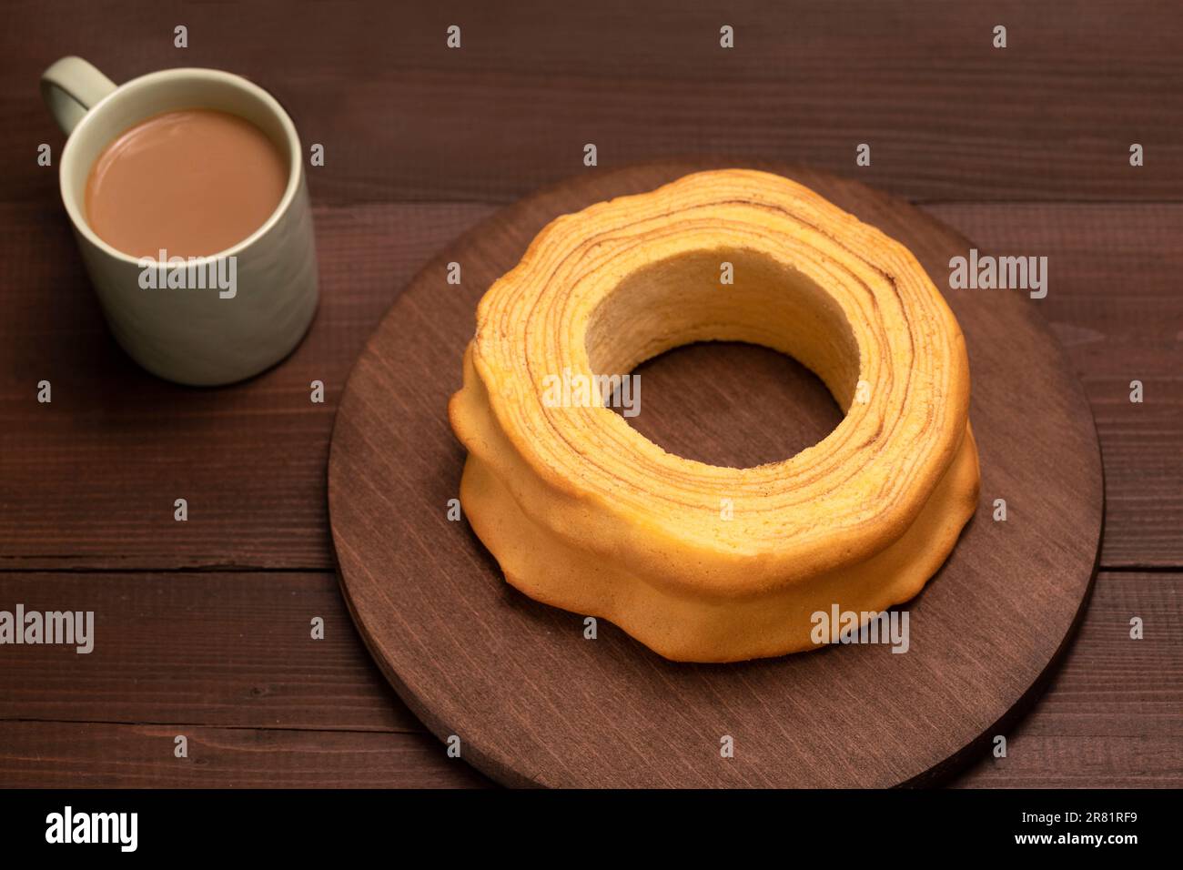 Blick von oben auf Baumkuchen, Sakotis, Sekacz auf braunem Holztisch, köstlicher hausgemachter traditioneller Spuckkuchen mit einer Tasse Kaffee. Horizontale Ebene, flach Stockfoto