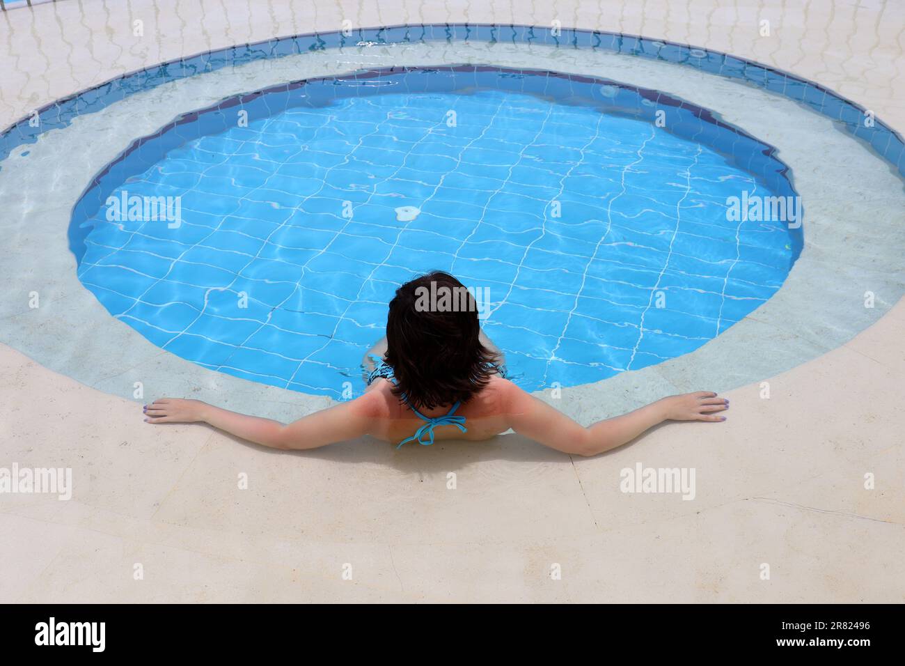 Junge Frau, entspannen Sie sich im durchsichtigen Wasser des Whirlpools im Swimmingpool Stockfoto