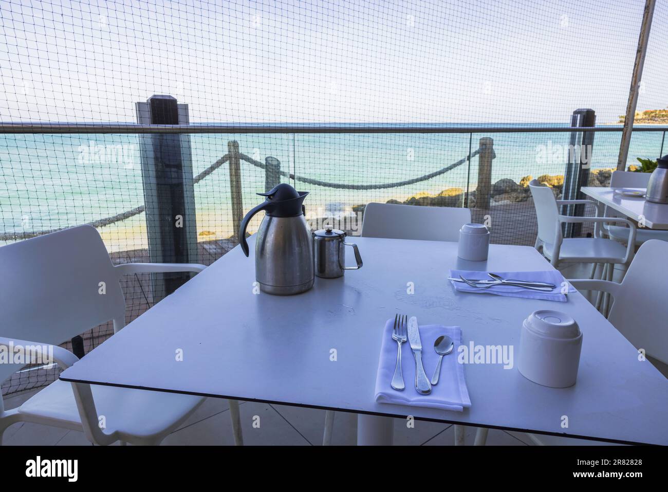Nahansicht des Tisches mit Besteck zum Frühstück im Freiluftrestaurant mit Blick auf den Atlantischen Ozean. Aruba. Stockfoto