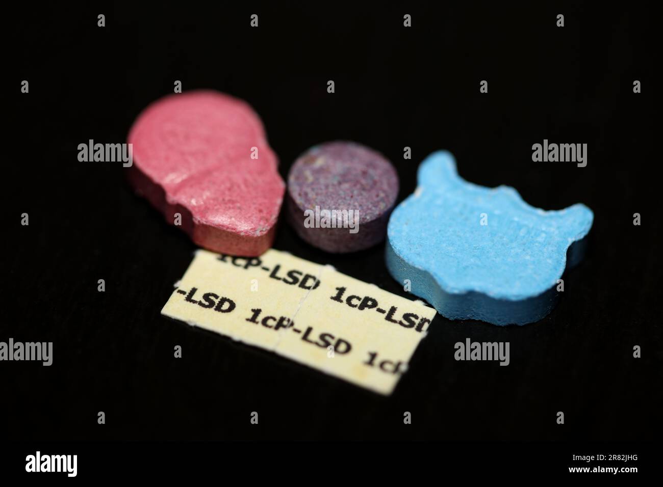 Eine Mischung aus Medikamenten- und Medikamentenpillen, die mdma- und lsd-Stick-Papiere enthalten, zeigt den Hintergrund von Partytieren mit extragroßen Tanzabdrücken Stockfoto