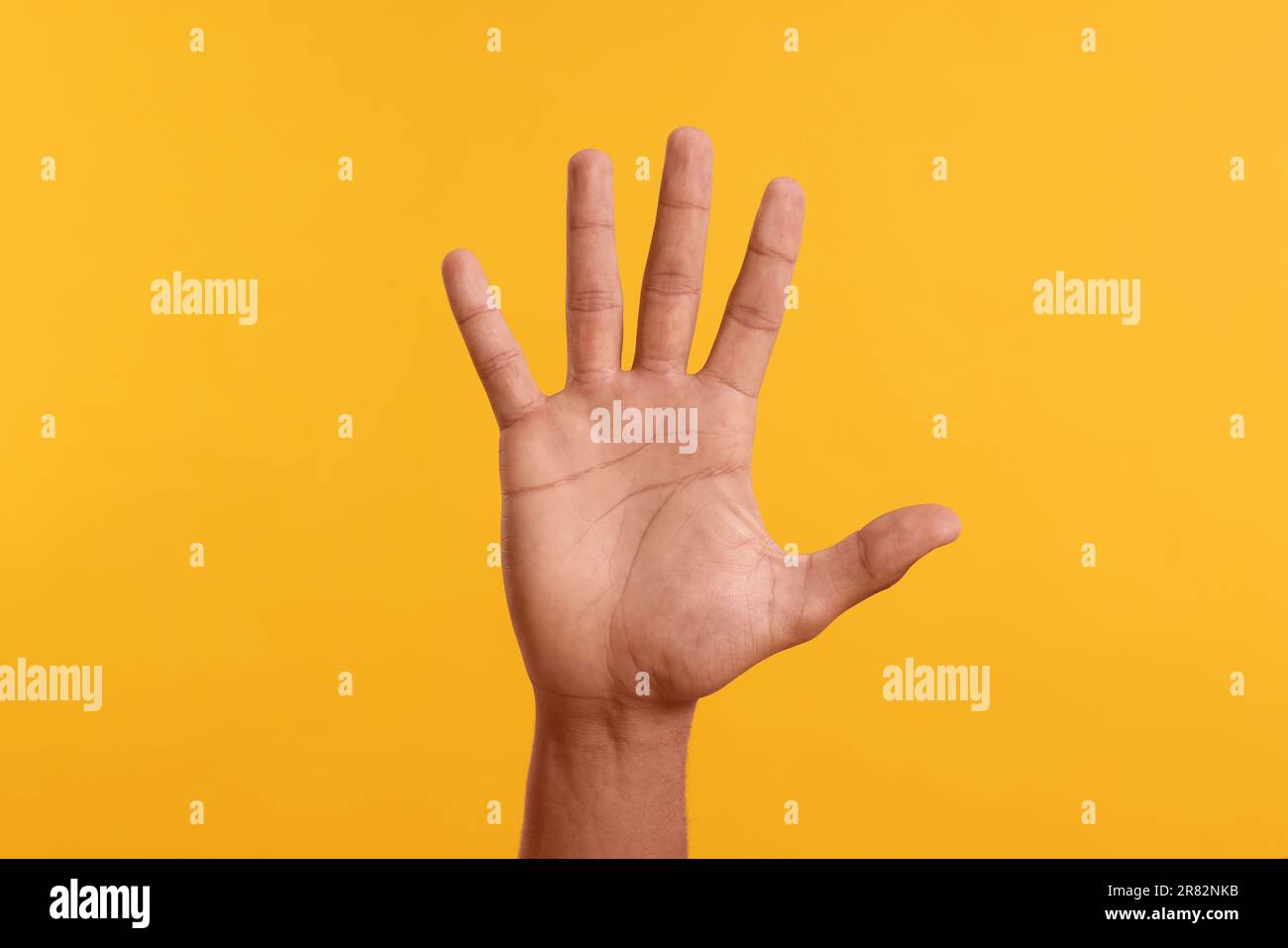 Ein Mann gibt High Five auf gelbem Hintergrund, Nahaufnahme der Hand Stockfoto