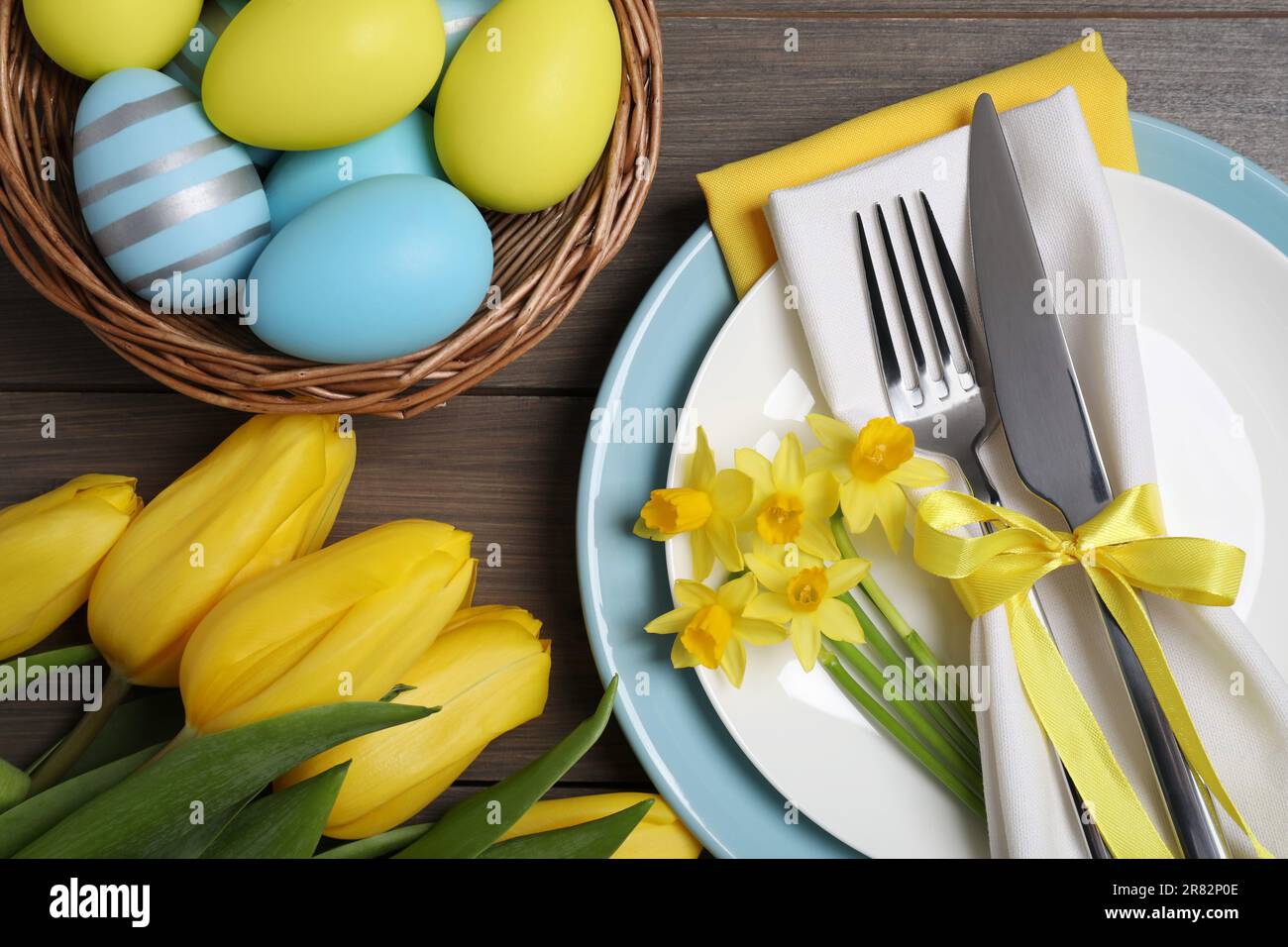 Festlicher Tisch mit Blumen und bemalten Eiern auf Holzhintergrund. Osterfeier Stockfoto