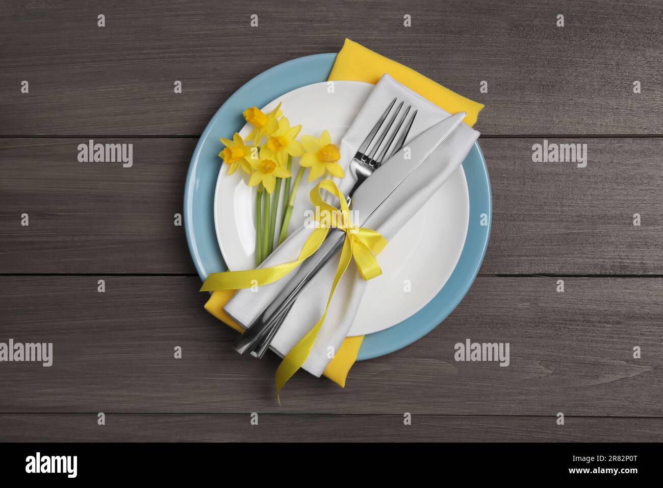 Festlicher Tisch mit Narzissen und Besteck auf Holzhintergrund, Draufsicht. Osterfeier Stockfoto