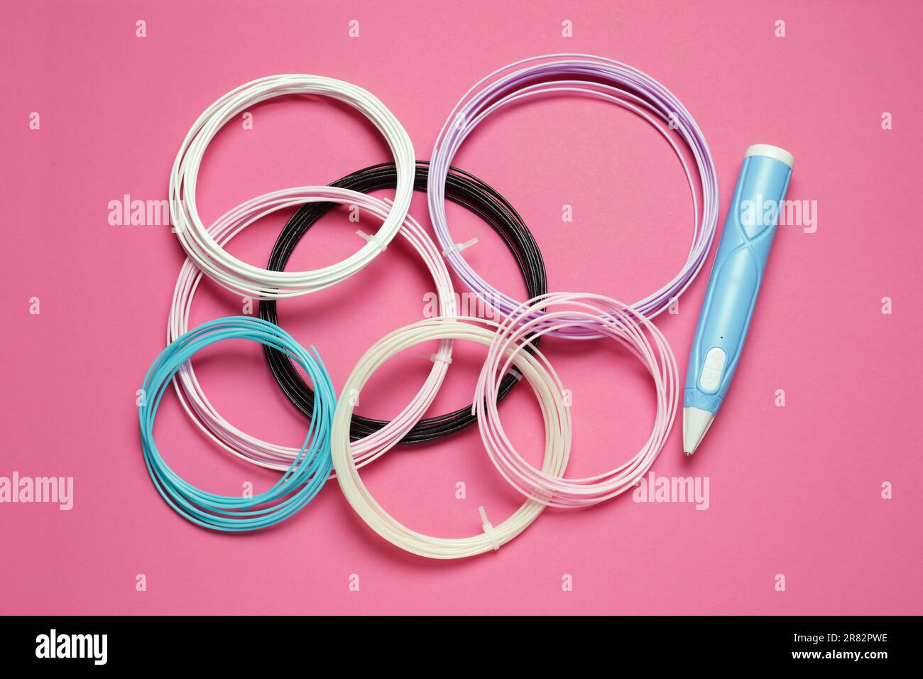 Eleganter 3D-Stift und farbenfrohe Kunststofffilamente auf pinkfarbenem Hintergrund, flach liegend Stockfoto
