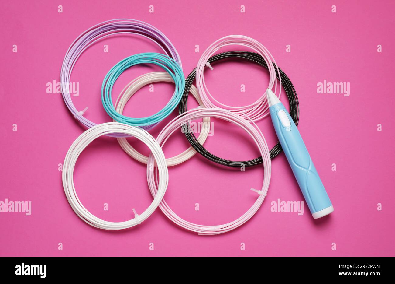 Eleganter 3D-Stift und farbenfrohe Kunststofffilamente auf pinkfarbenem Hintergrund, flach liegend Stockfoto