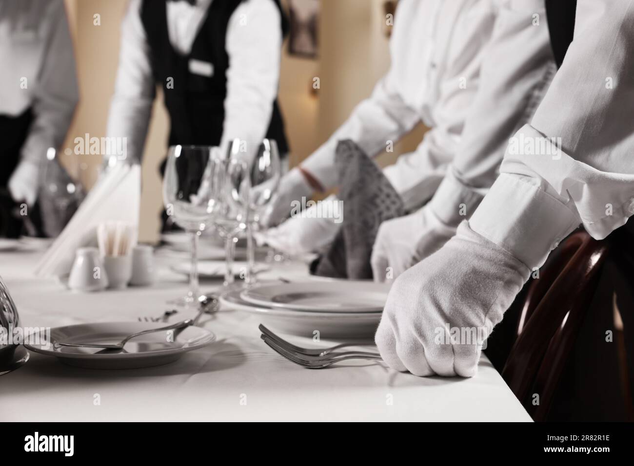 Leute, die den Tisch während professioneller Butler-Kurse im Restaurant eindecken, schließen Stockfoto