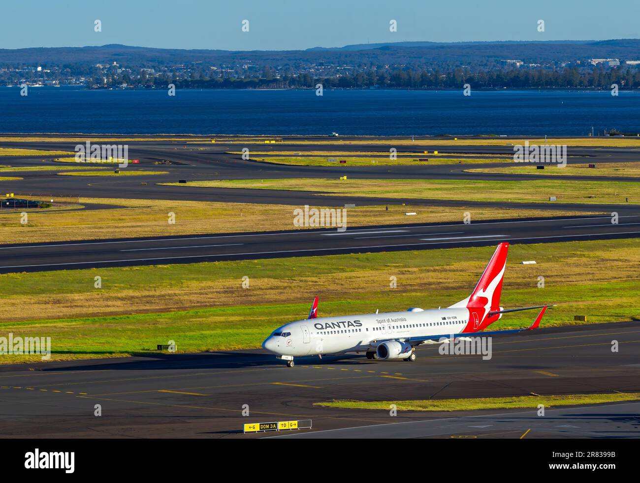 Flugbewegungen am Flughafen Sydney (Kingsford Smith) in Australien, mit Botany Bay im Hintergrund. Abbildung: Ein Qantas Jet mit Registrierung VH-VX Stockfoto