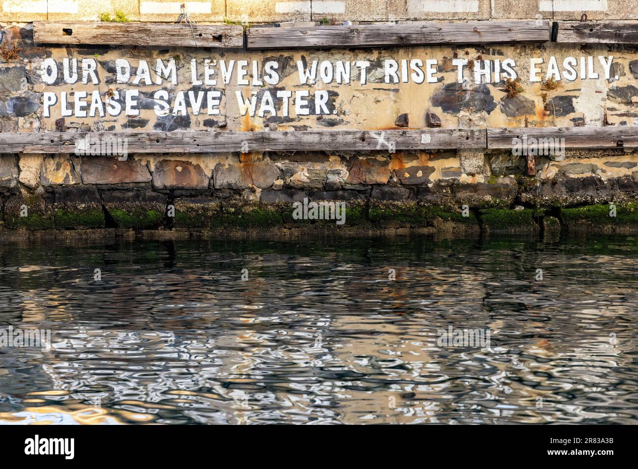 „Unsere Staudammpegel werden nicht so leicht steigen. Bitte sparen Sie Wasser' Graffiti an der V&A Waterfront - Kapstadt, Südafrika Stockfoto