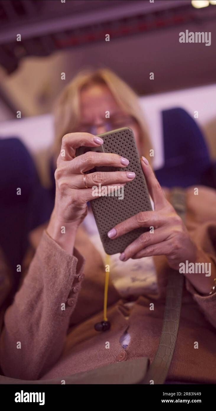 Nahaufnahme der Hände einer erwachsenen Frau mit einem Smartphone während der Fahrt mit dem Zug, Soft Focus Stockfoto