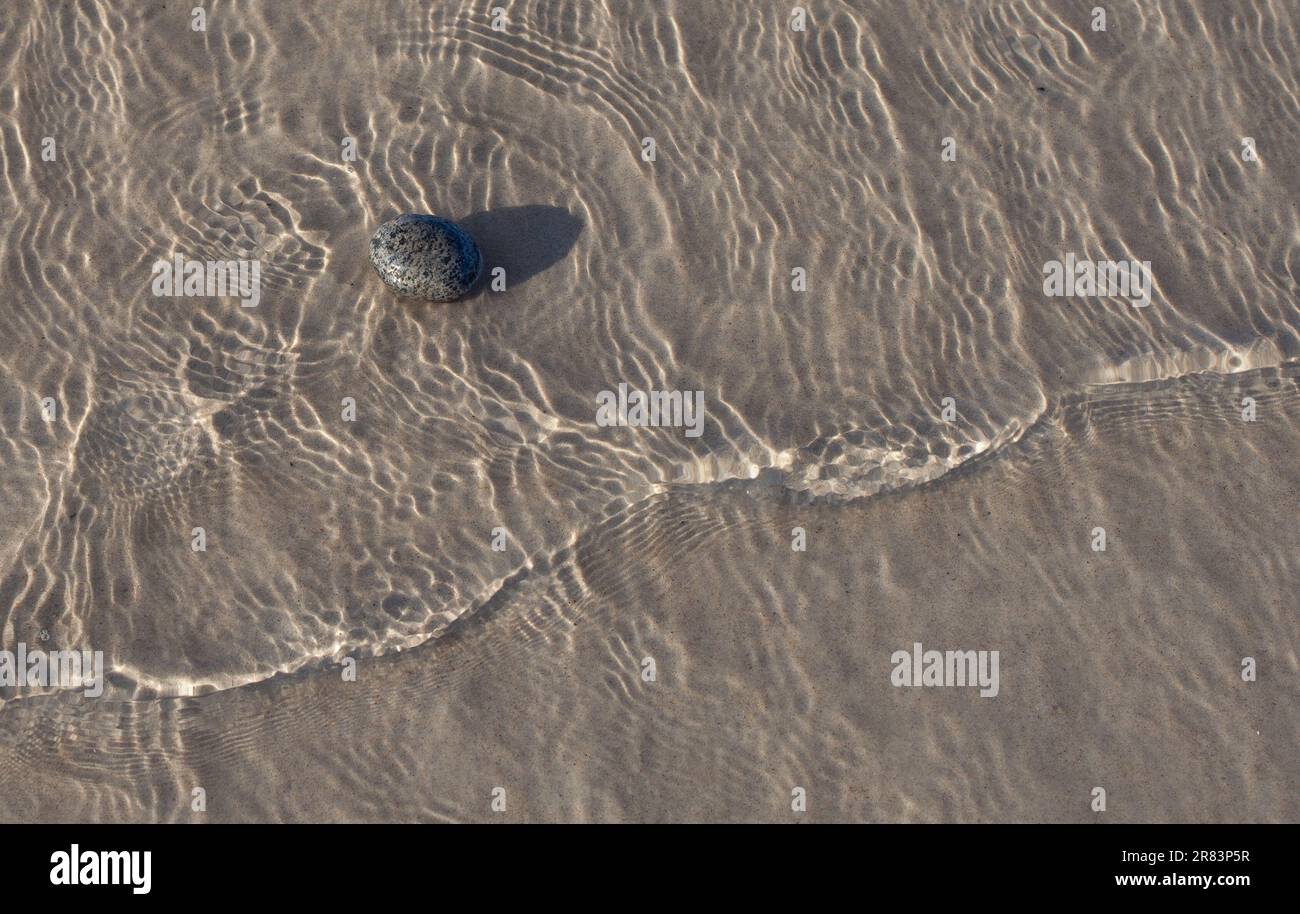 Minimalistische Komposition mit Platz für Text. Stein am Ufer des Strandes von oben geschossen. Stockfoto