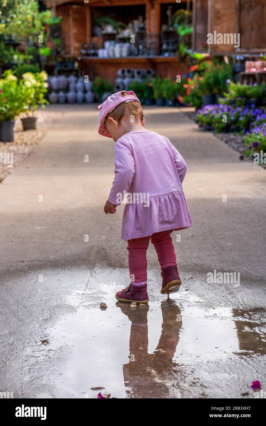 Ein kleines Kind spielt in einer Regenpfütze Stockfoto