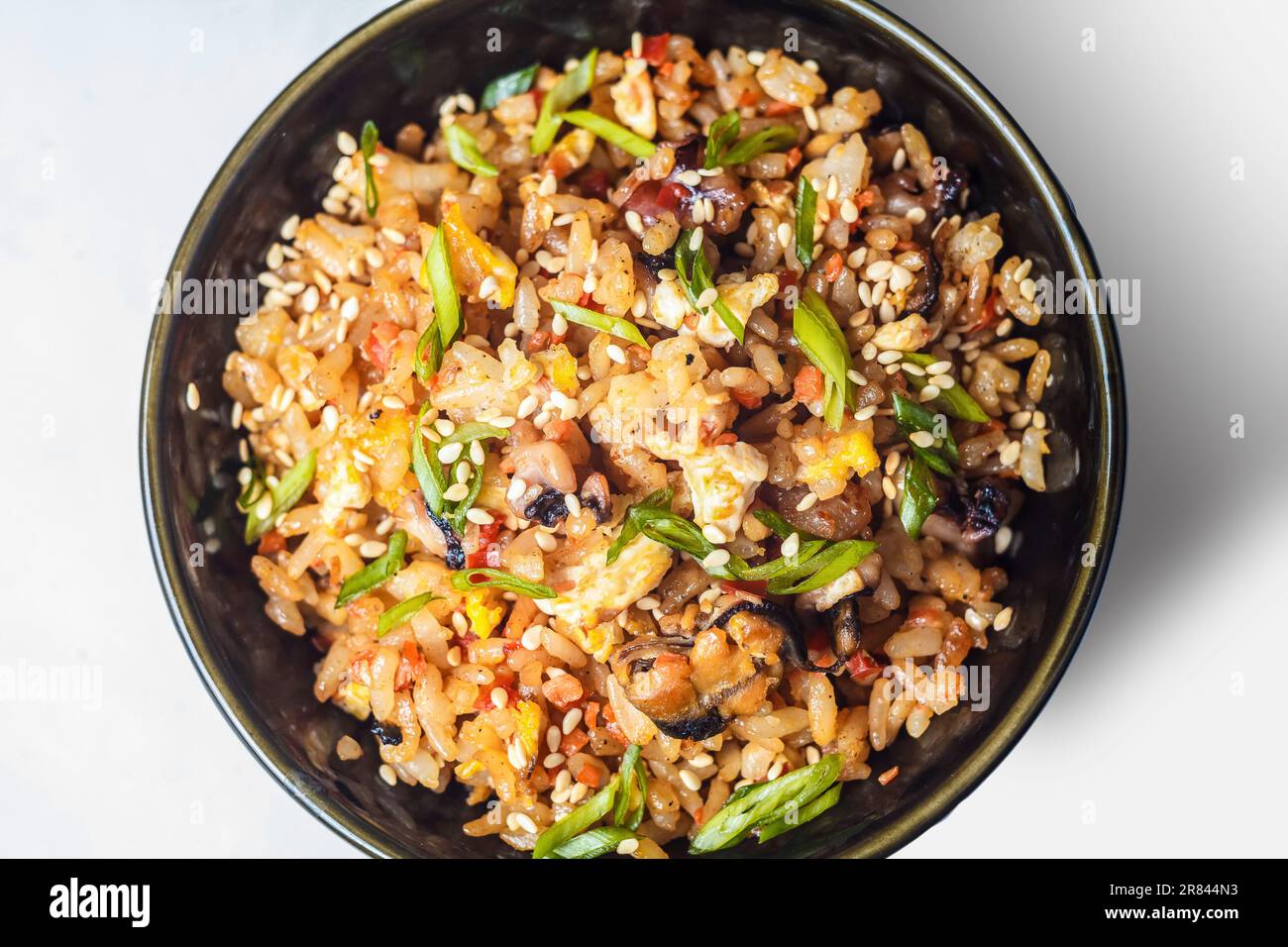 Ein brutzelnder Wok gefüllt mit einer köstlichen Mischung aus Gemüse, Linsen, Reis und Fleisch, der ein aromatisches und gesundes vegetarisches Gericht zum Abendessen schafft. Stockfoto