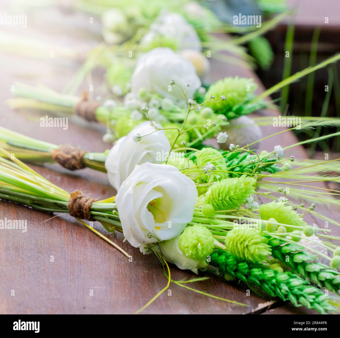 Weiße Brautsträuße in einer Reihe auf einem Holztisch. Hochzeitsdekoration. Weiße Rosen. Selektiver Fokus Stockfoto