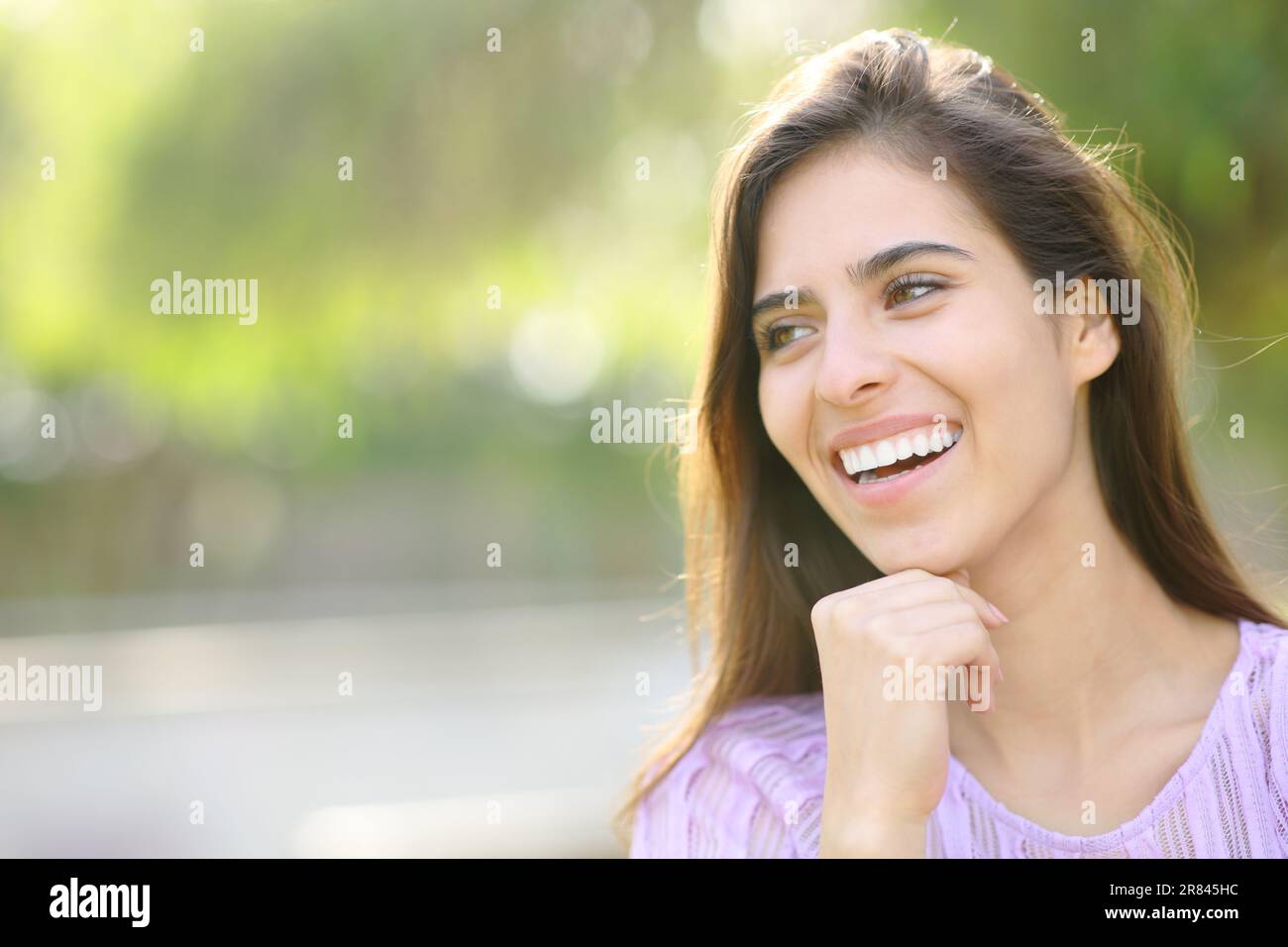 Glückliche Frau mit perfektem Lächeln, die in einem Park wegschaut Stockfoto