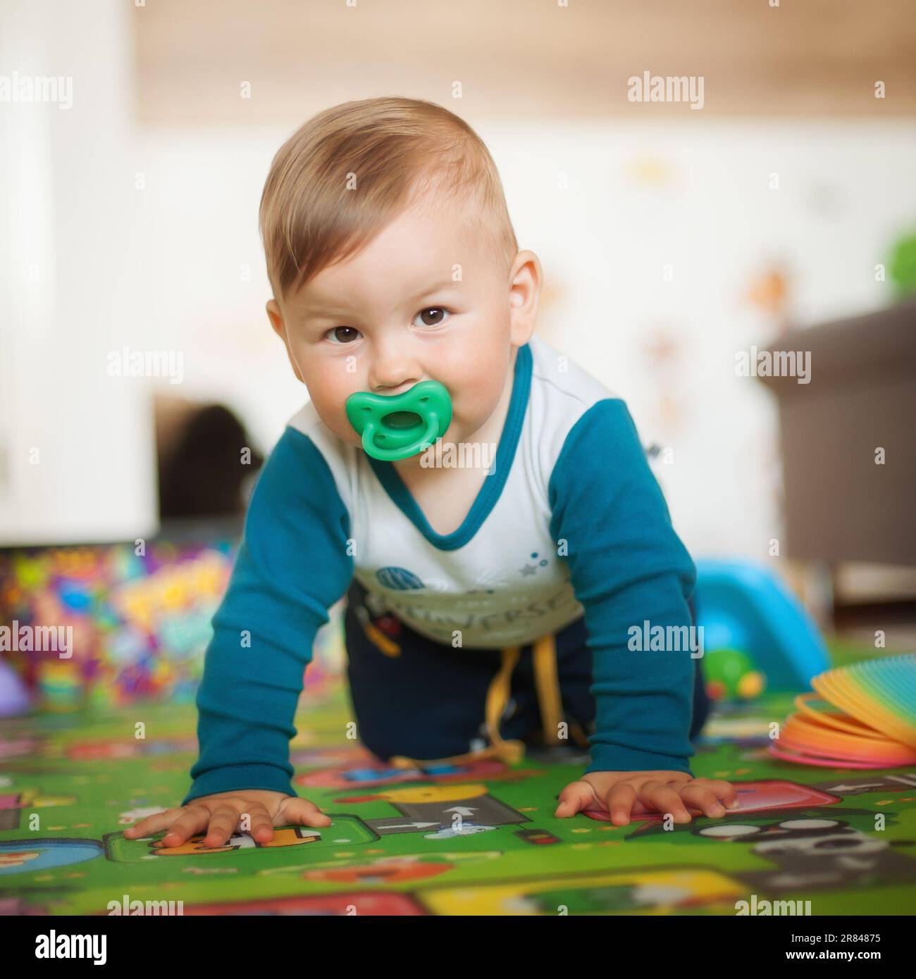 Porträt eines süßen, fröhlichen, lächelnden Jungen, der auf dem Hausboden krabbelt und in die Kamera schaut. Das Konzept von Freude und Glück. Vorderansicht. Liebe und Familiengefühle Stockfoto