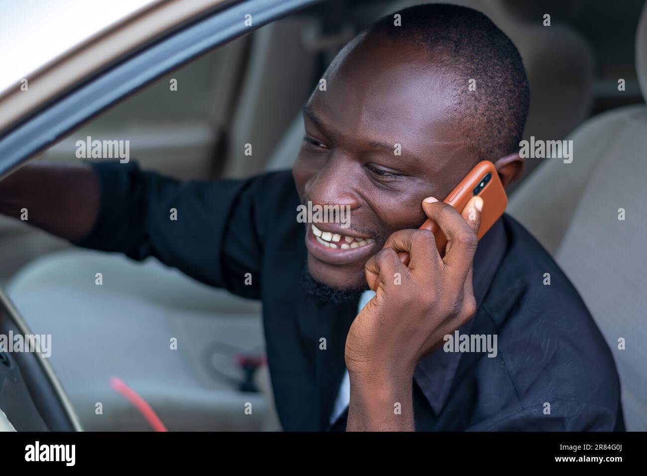 afrikanischer Fahrer und Geschäftsmann verwendet ein Smartphone für die drahtlose Kommunikation Stockfoto