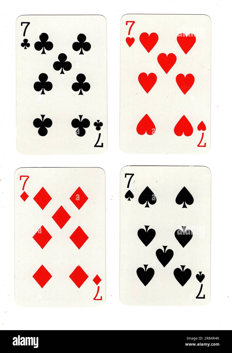 Vintage-Spielkarten mit vier Siebenen auf weißem Hintergrund. Stockfoto