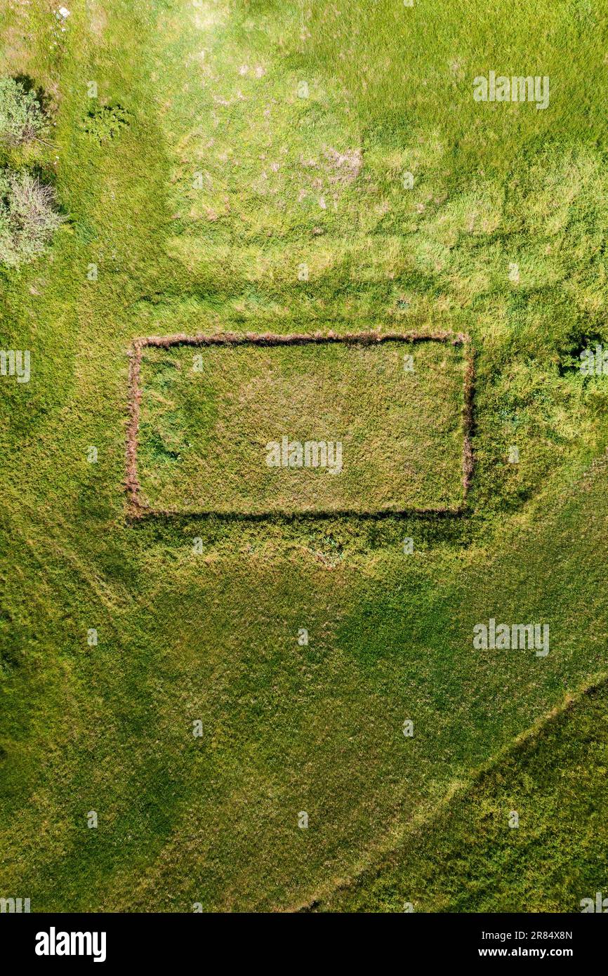 Luftaufnahme eines unvollendeten Hausfundamentes auf dem Grasfeld von der Drohne pov, rechteckige Form auf der Wiese als Hintergrundbild für soziale Medien, Draufsicht Stockfoto