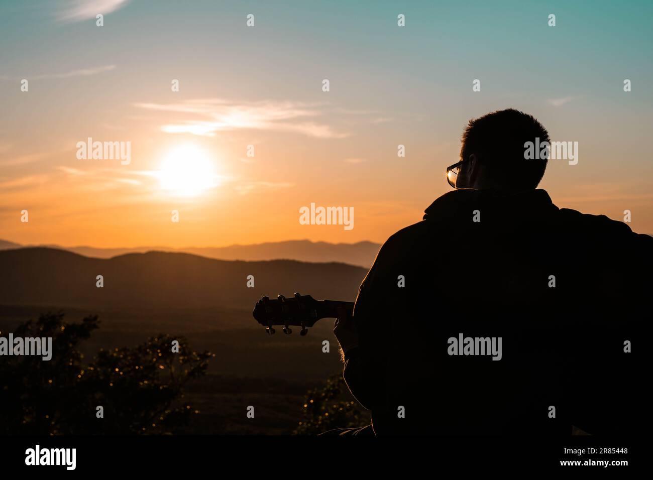 Mann mit Gitarrensilhouette und Blick auf die Berge in der slowakischen Landschaft bei schönem Sonnenuntergang Stockfoto