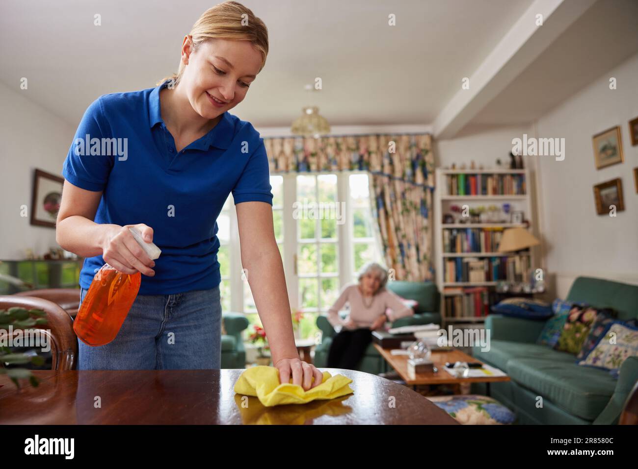 Weibliches Zuhause Hilfe Reinigung Haus Und Im Gespräch Mit Älteren Frau Stockfoto